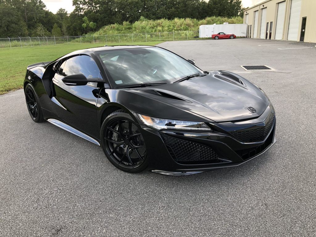 A black sports car is parked in a parking lot.