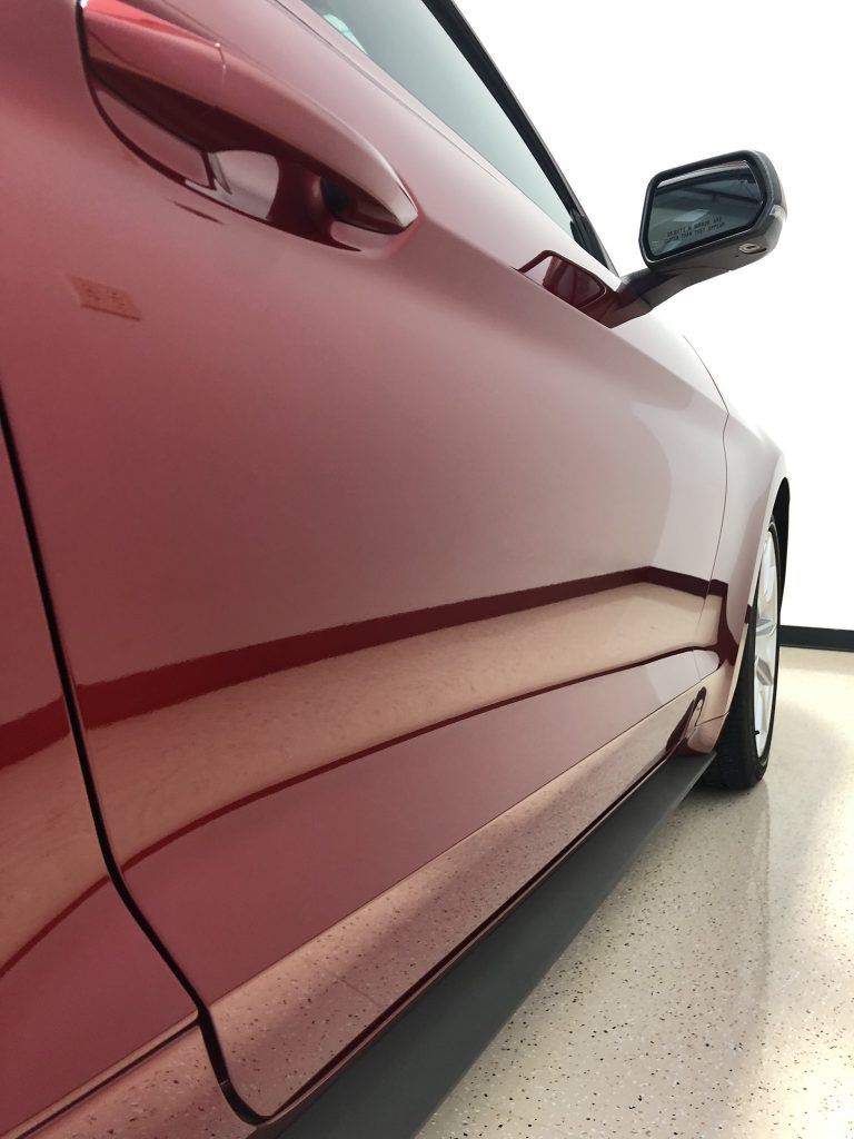 A red ford mustang is parked in a garage.