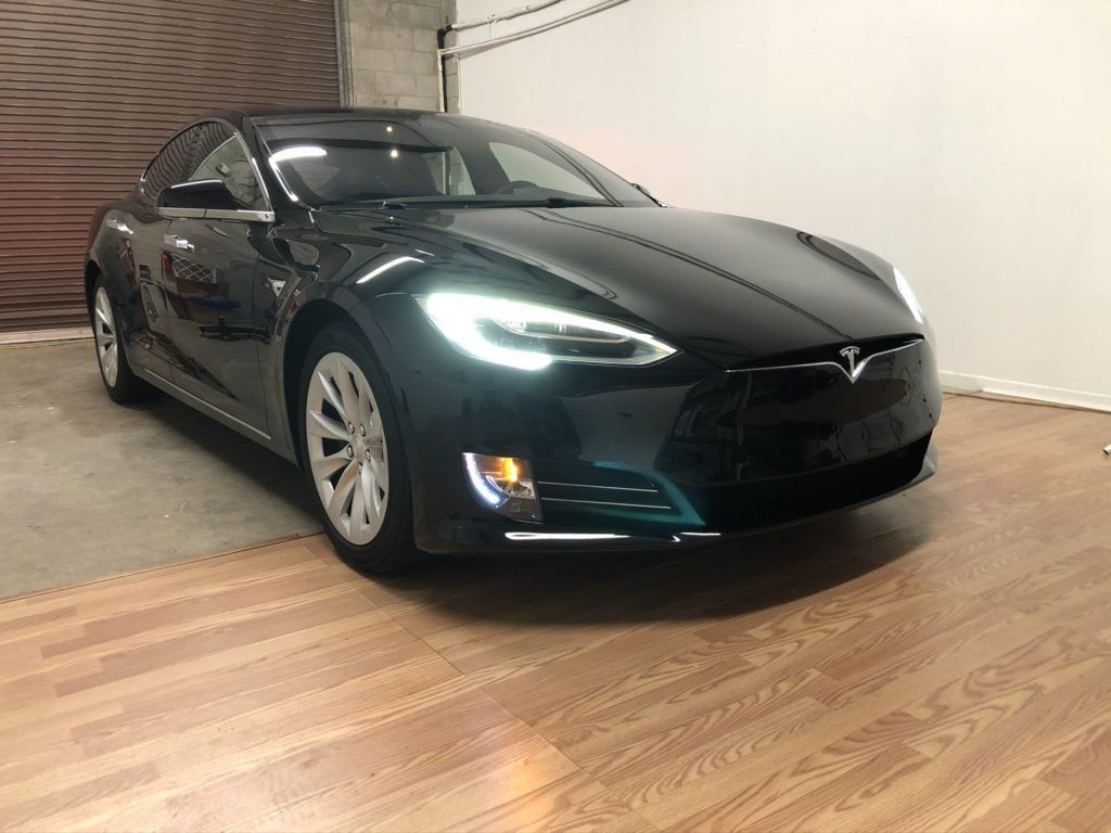 A black tesla model s is parked in a garage.