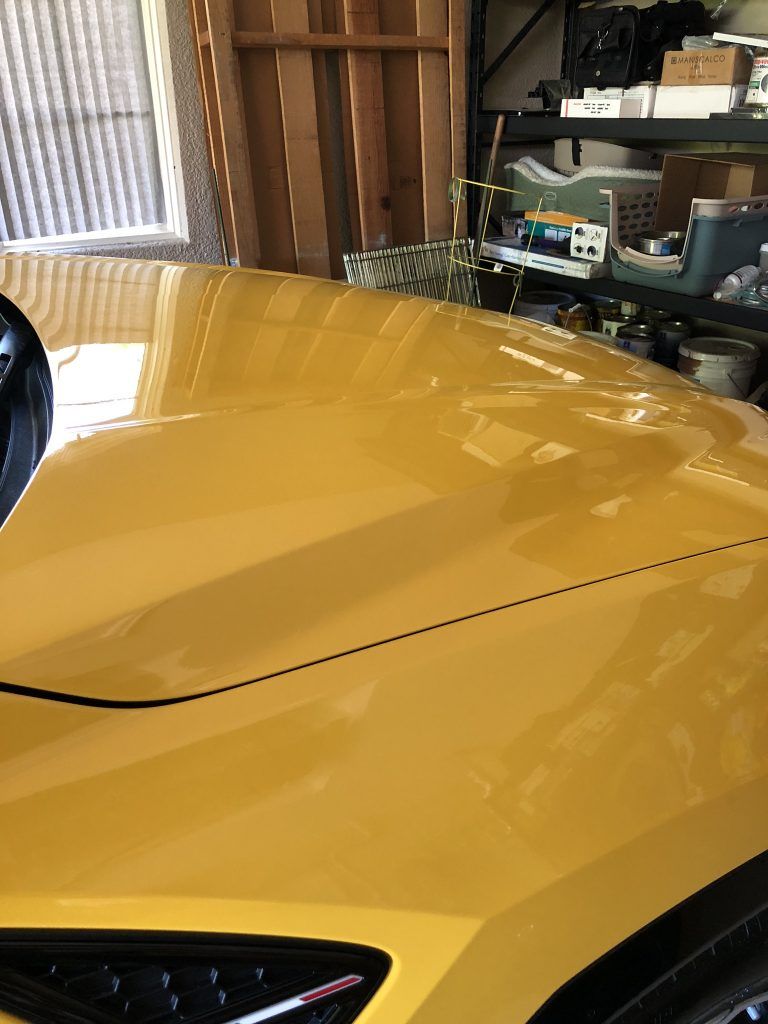 A yellow sports car is parked in a garage.