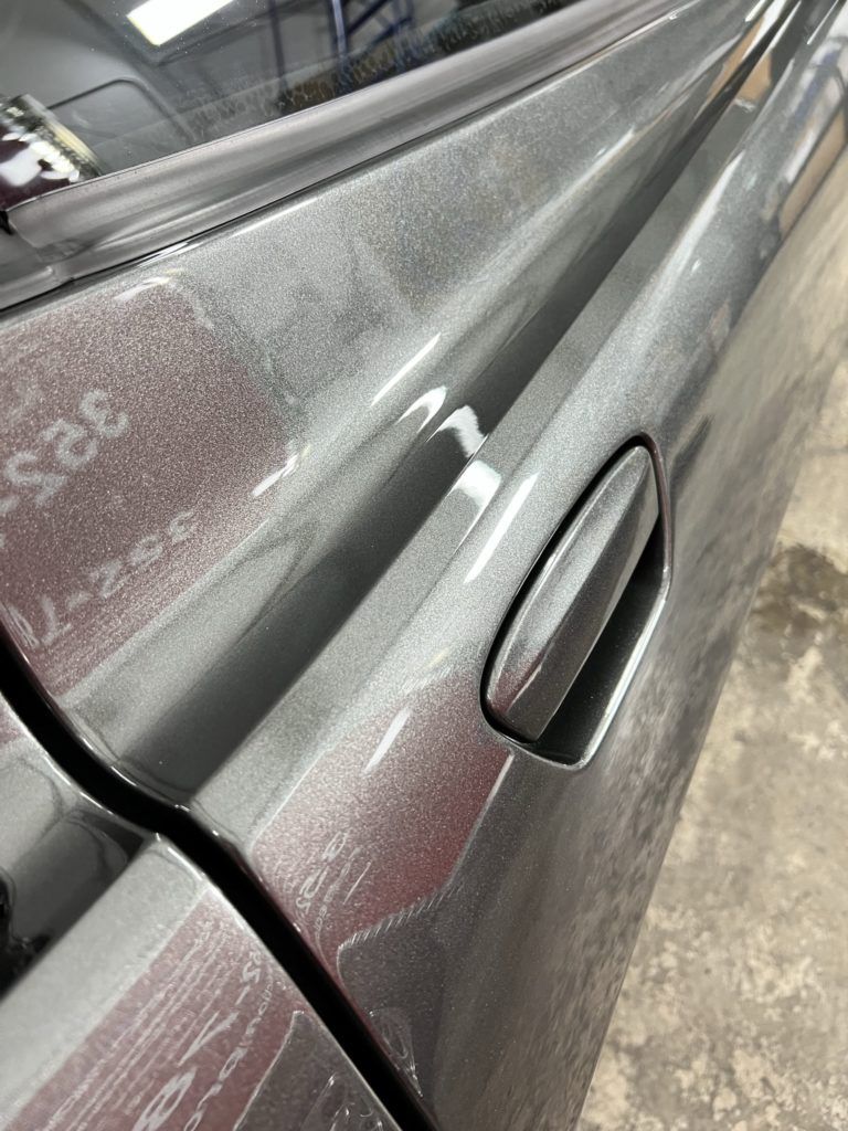 A close up of a gray car door in a garage.