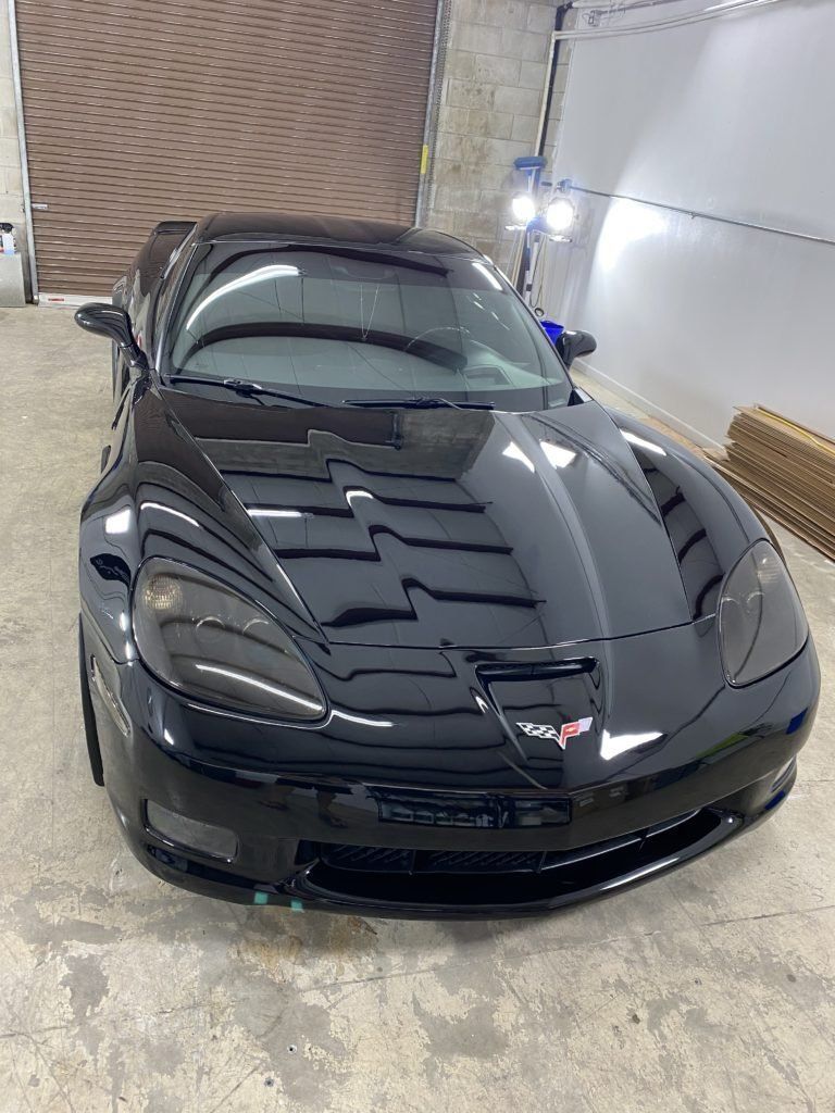 A black sports car is parked in a garage.