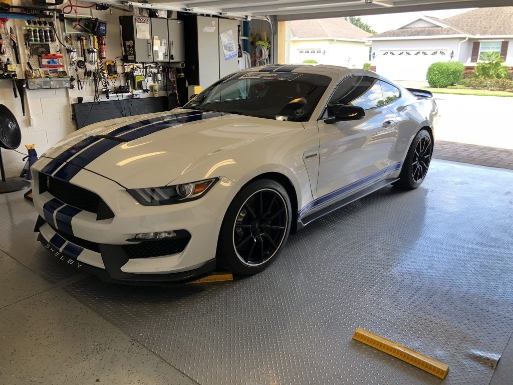 A white ford mustang is parked in a garage.