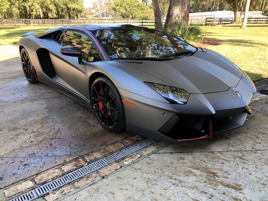 A black lamborghini aventador is parked in a driveway.