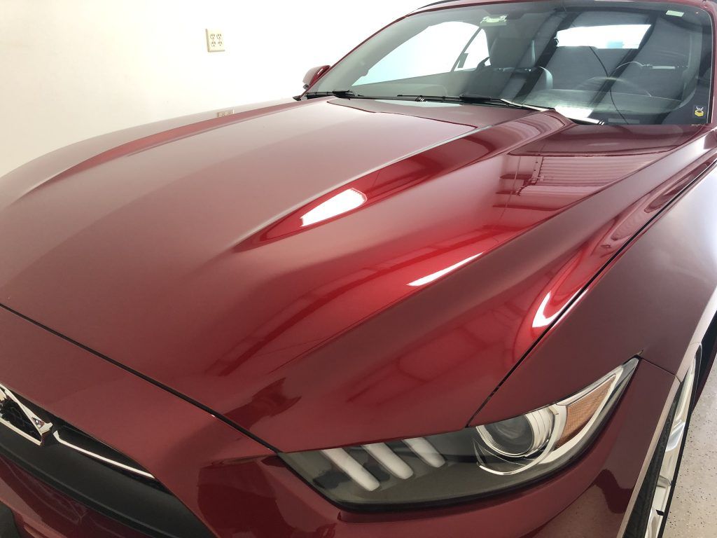 A red ford mustang is parked in a garage.