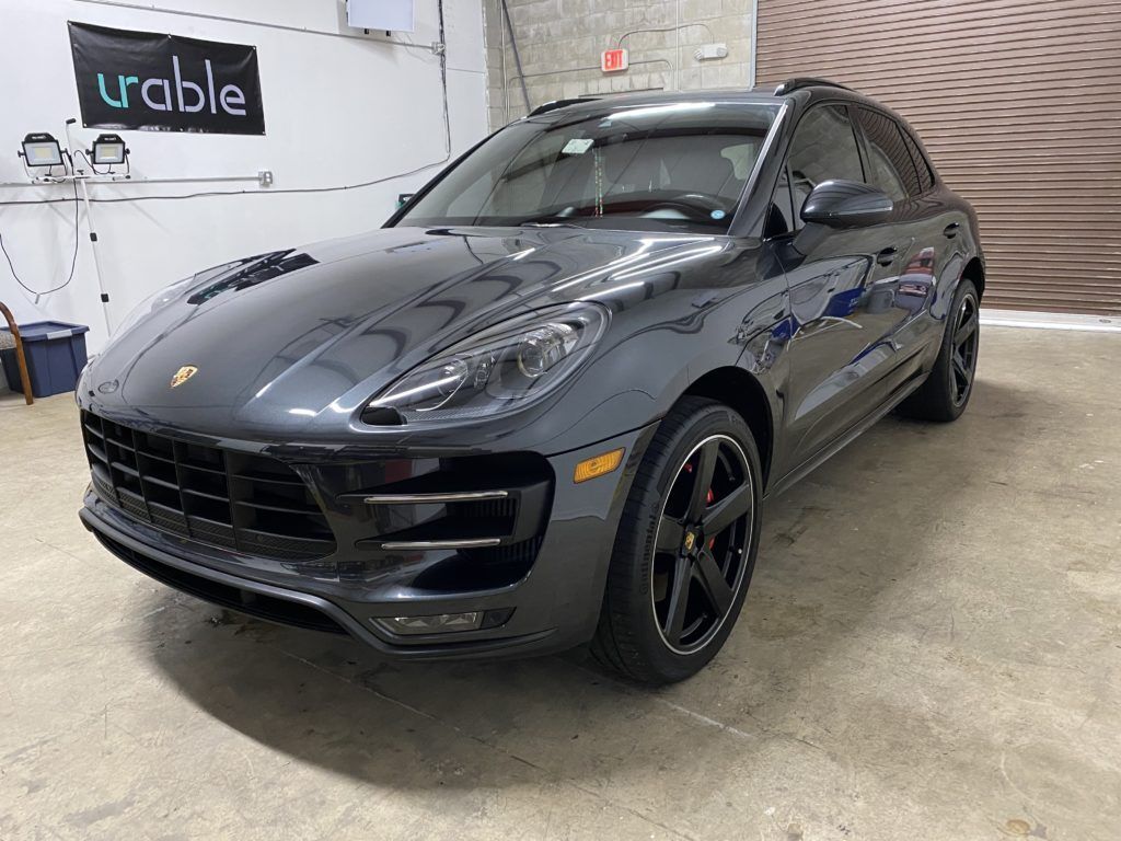 A gray porsche macan turbo is parked in a garage.