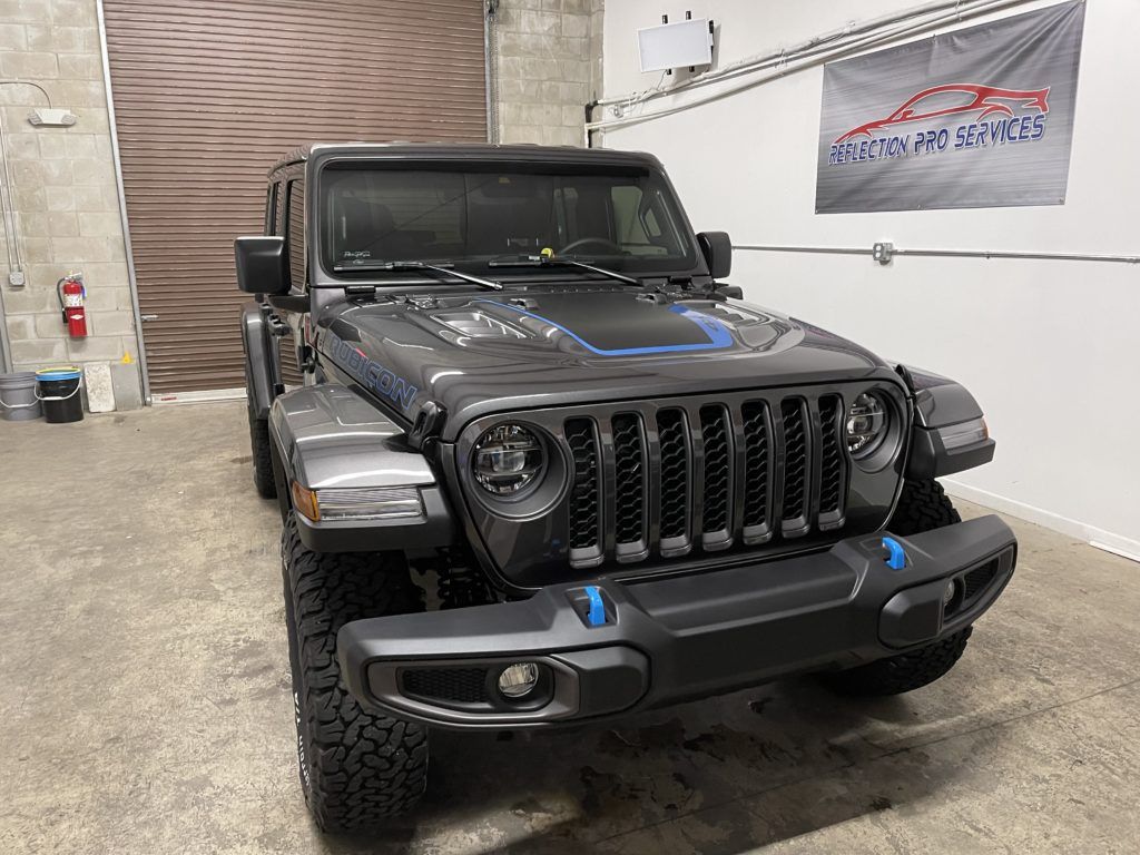 A jeep wrangler is parked in a garage next to a garage door.