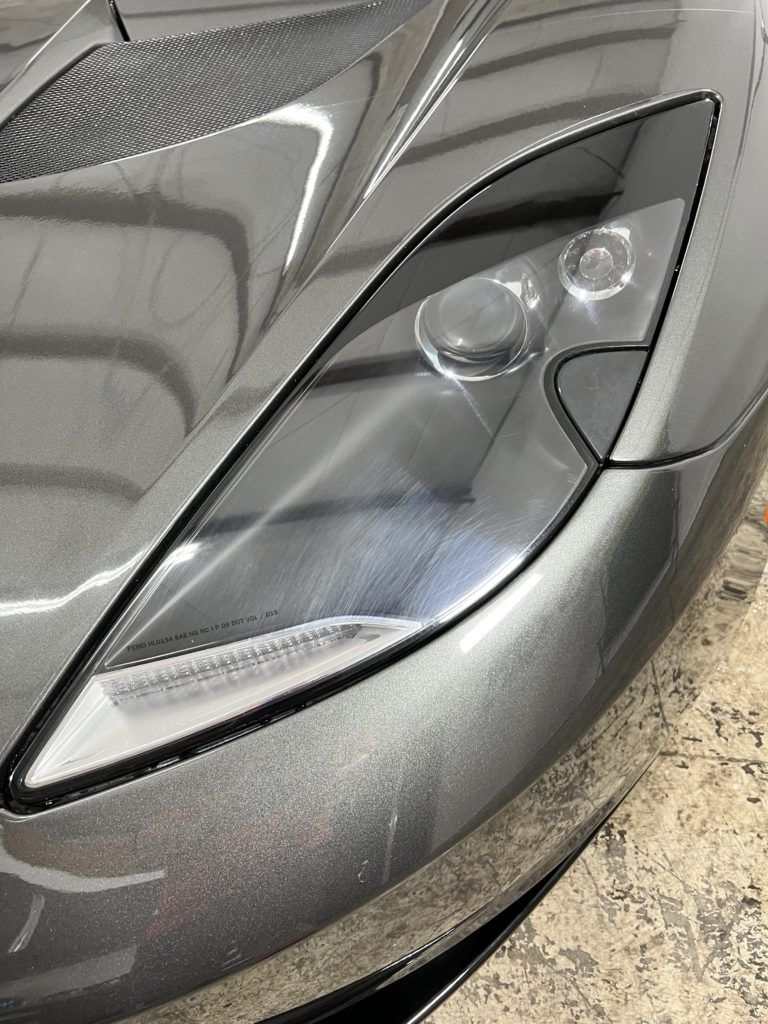 A close up of the headlights of a gray sports car.