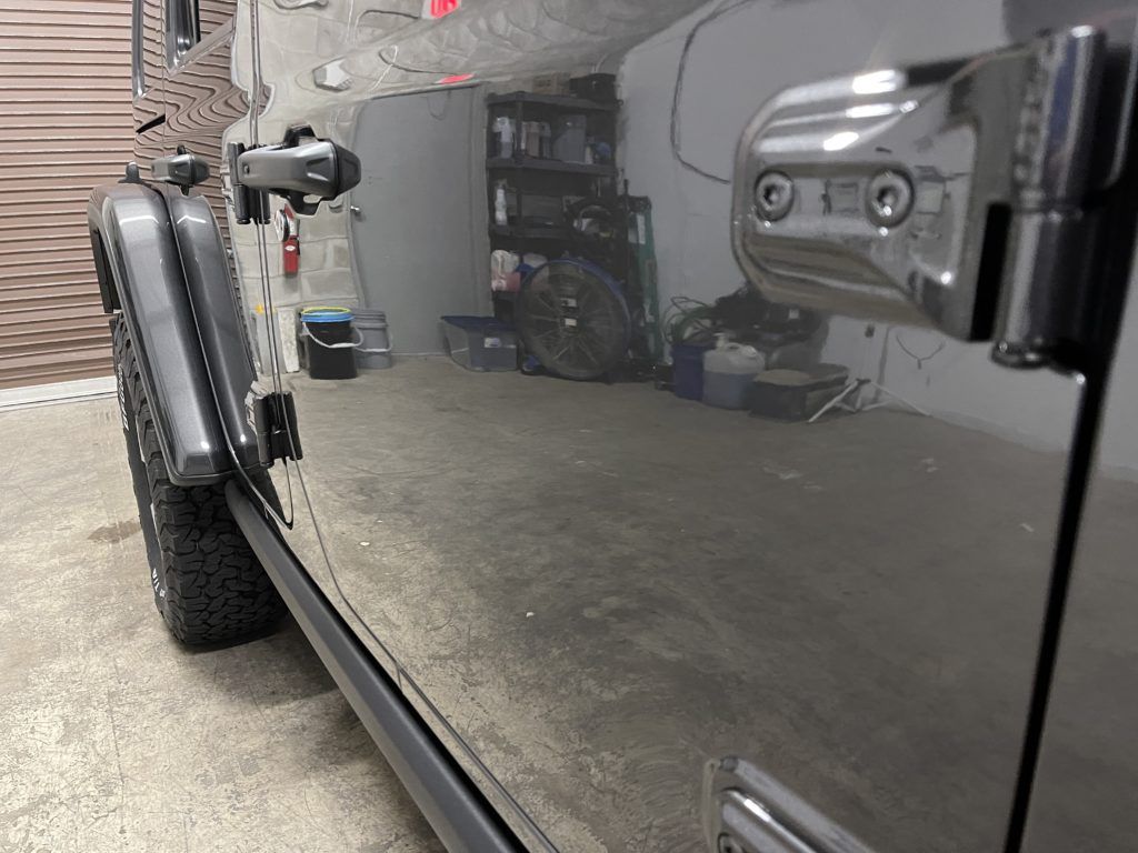 A black jeep is parked in a garage.