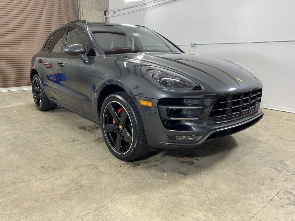 A gray porsche macan turbo is parked in a garage.