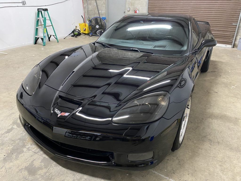 A black sports car is parked in a garage next to a ladder.