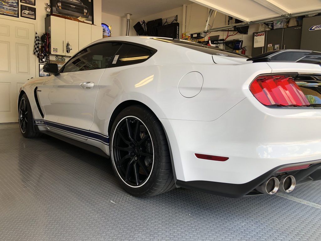A white mustang is parked in a garage.