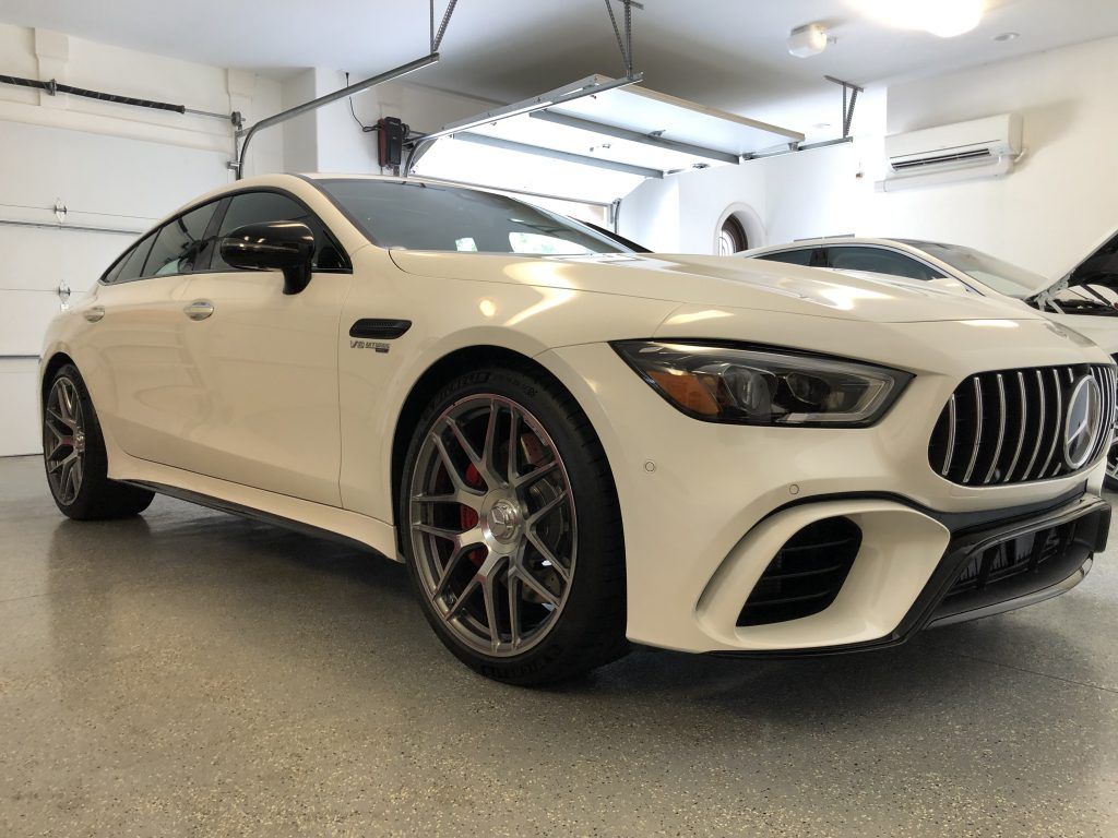 A white mercedes amg gt 63 s is parked in a garage.