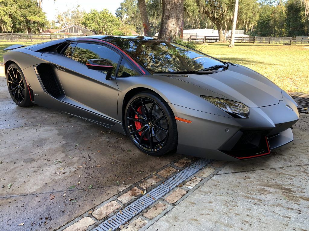 A black lamborghini aventador is parked in a driveway.