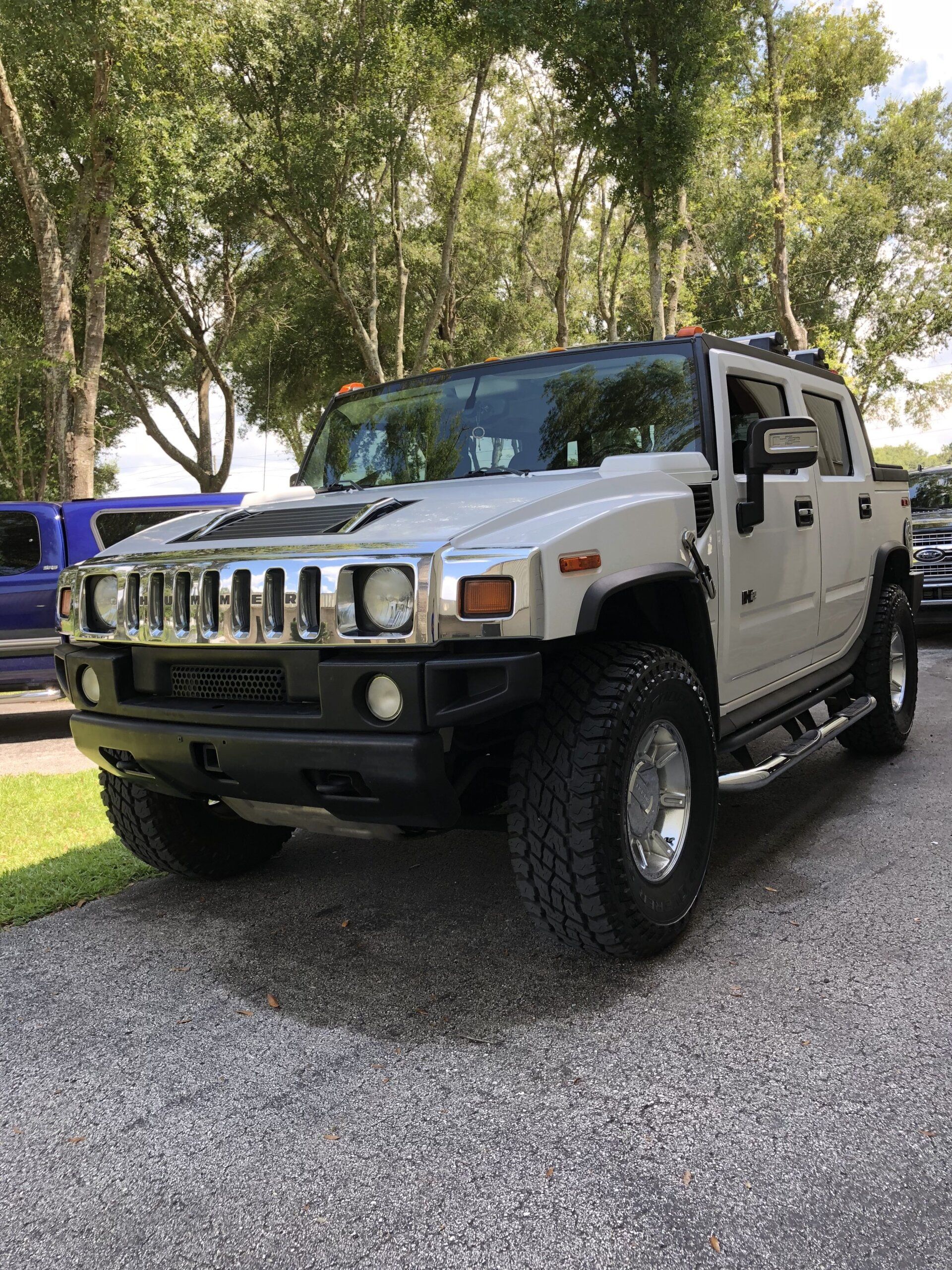 A white hummer h2 is parked in a gravel lot.