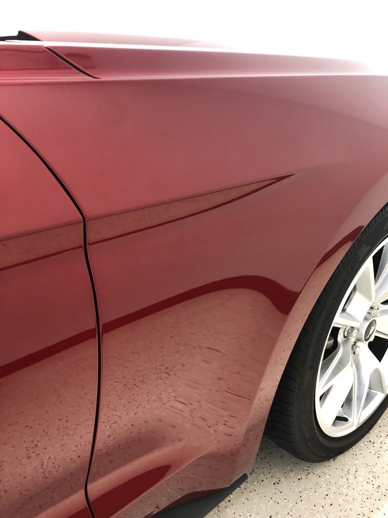 A red car is parked in a garage with the door open