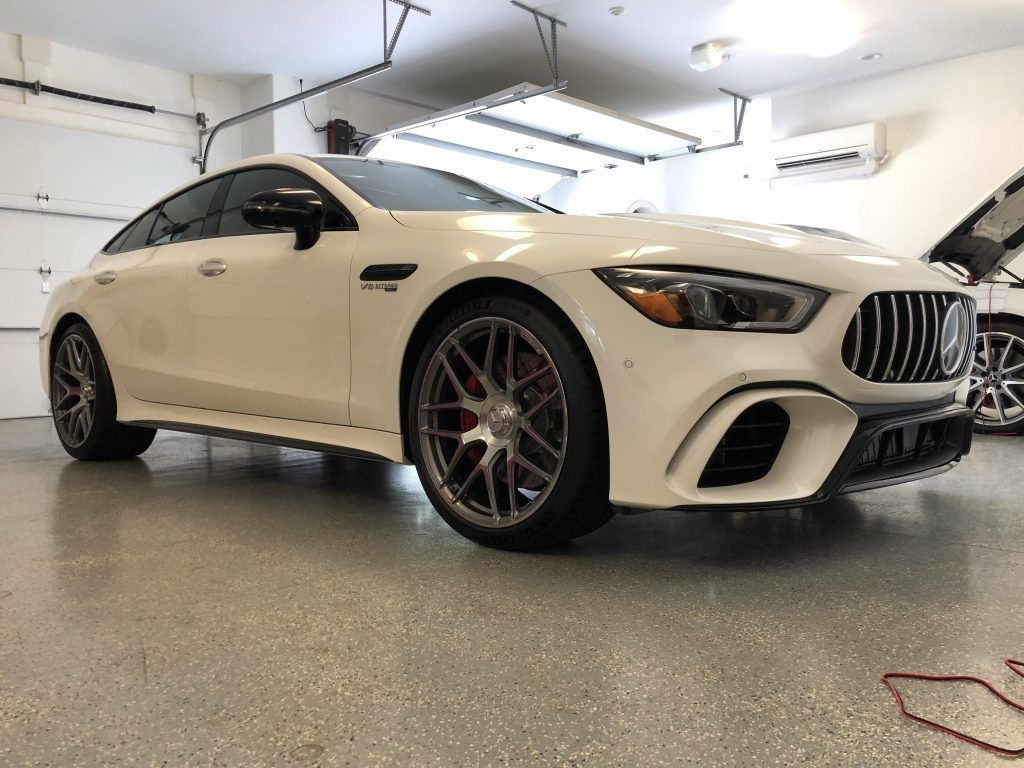 A white mercedes amg gt 63 s is parked in a garage.