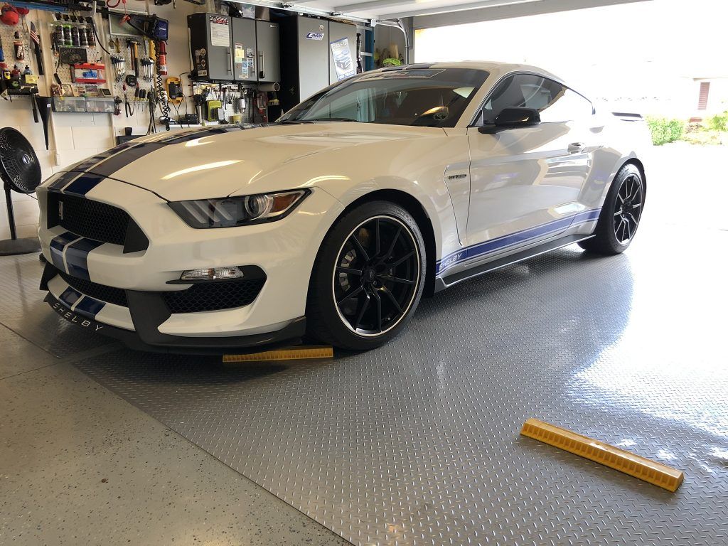 A white ford mustang is parked in a garage.