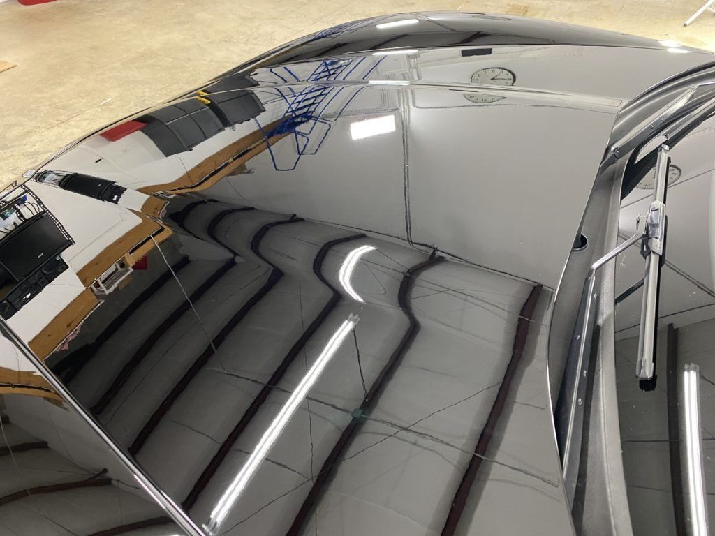 A car is reflected in a mirror on a tiled floor.