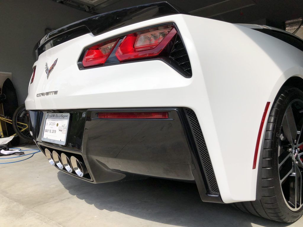 A white corvette is parked in a garage.