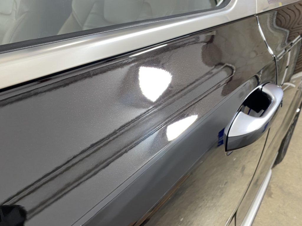 A close up of a black car door with a silver handle.