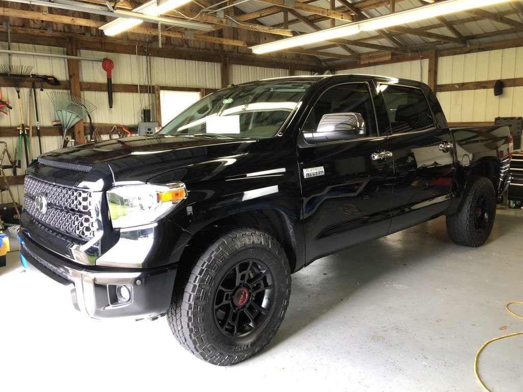 A black toyota tundra is parked in a garage.