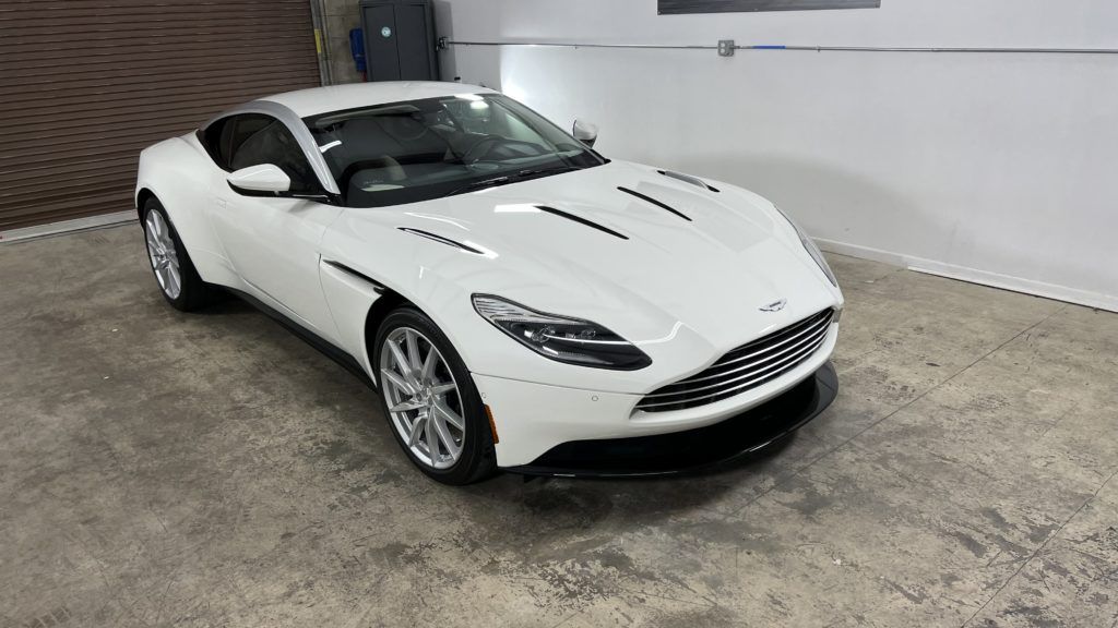 A white aston martin db11 is parked in a garage.