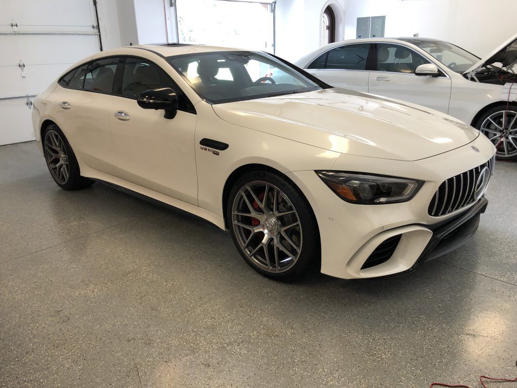 A white mercedes amg gt 63 s is parked in a garage.