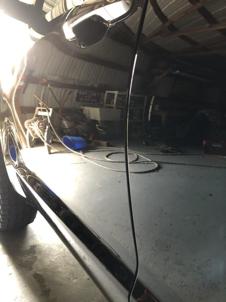 A car is parked in a garage with a hose attached to it.