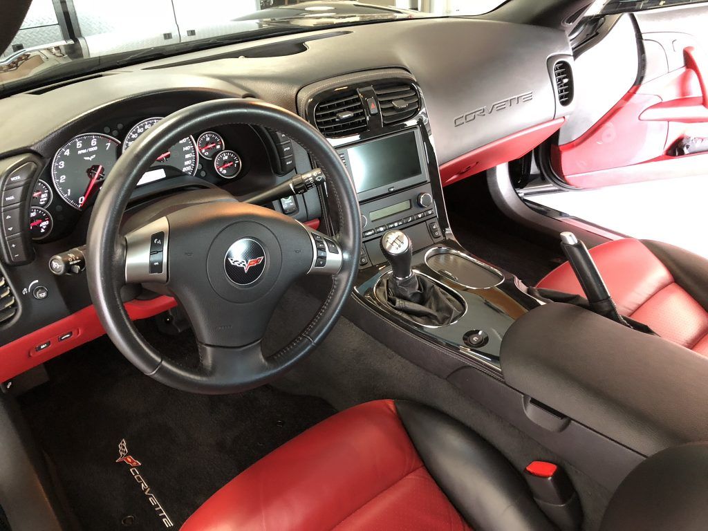 The interior of a corvette with red seats and a steering wheel.