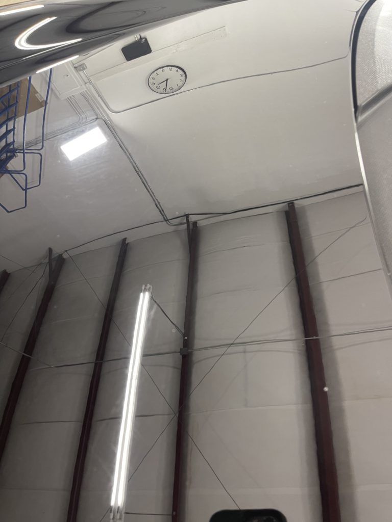A clock is hanging from the ceiling of a building.