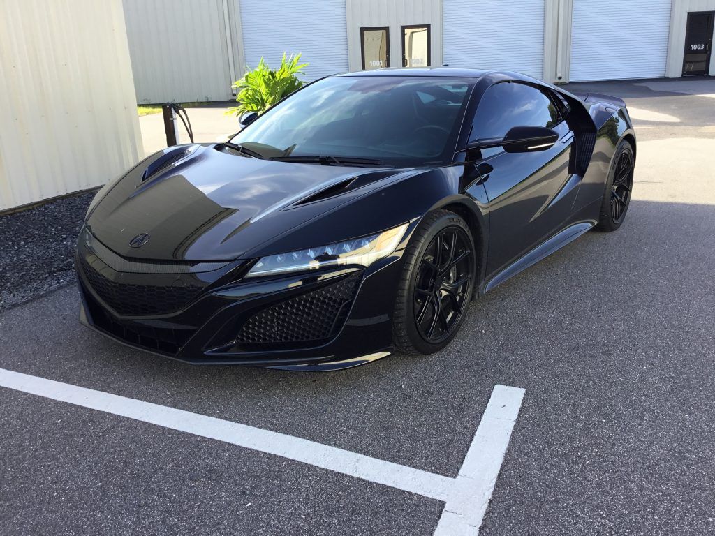 A black sports car is parked in a parking lot.