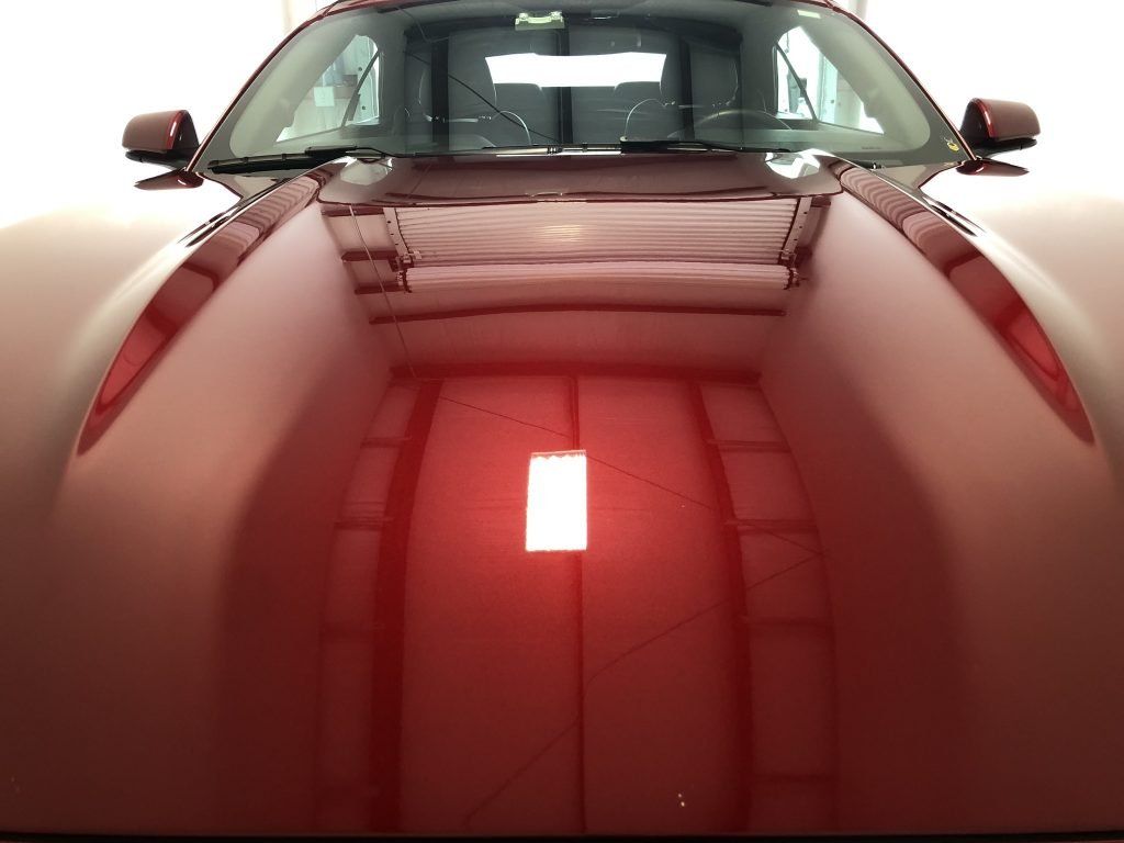 A red car is parked in a garage with a white background
