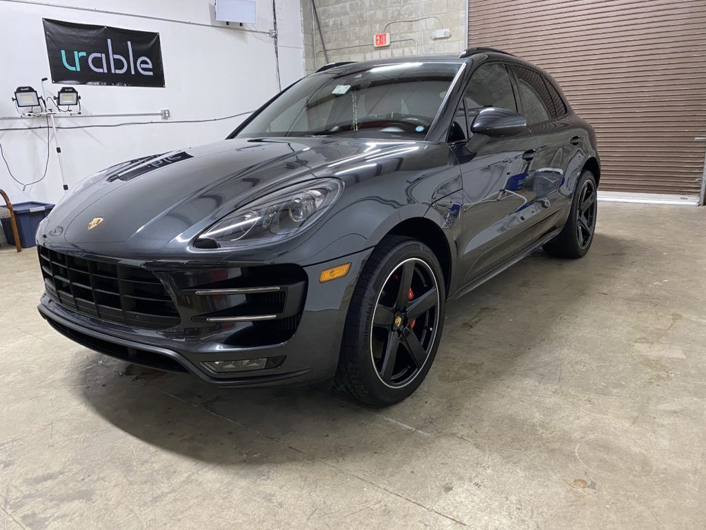 A gray porsche macan turbo is parked in a garage.