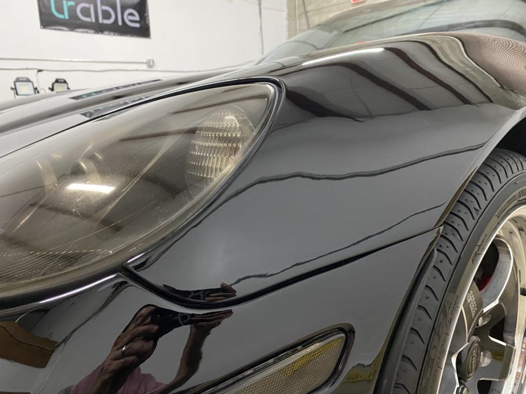 A close up of a black car 's headlight and tire