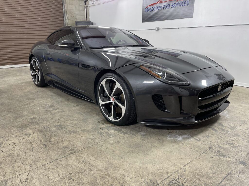 A black jaguar f type is parked in a garage.