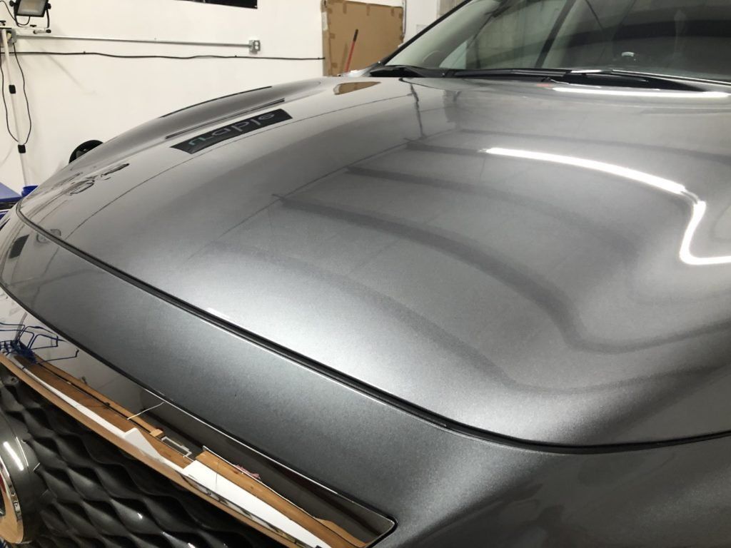 A close up of a car 's hood in a garage.