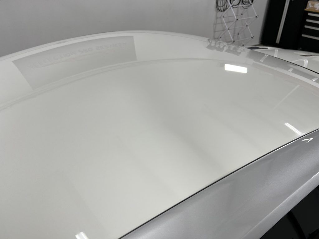 A close up of a white car 's roof in a garage.
