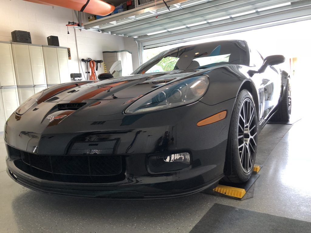 A black sports car is parked in a garage on a ramp.