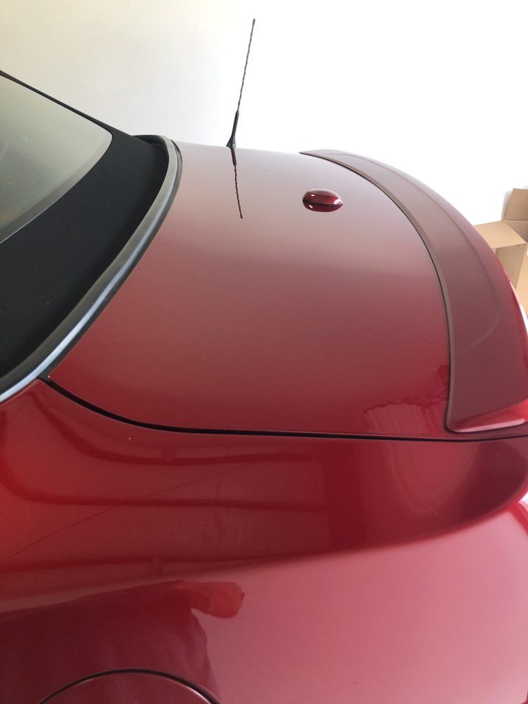 A red car with a spoiler on the back is parked in a garage