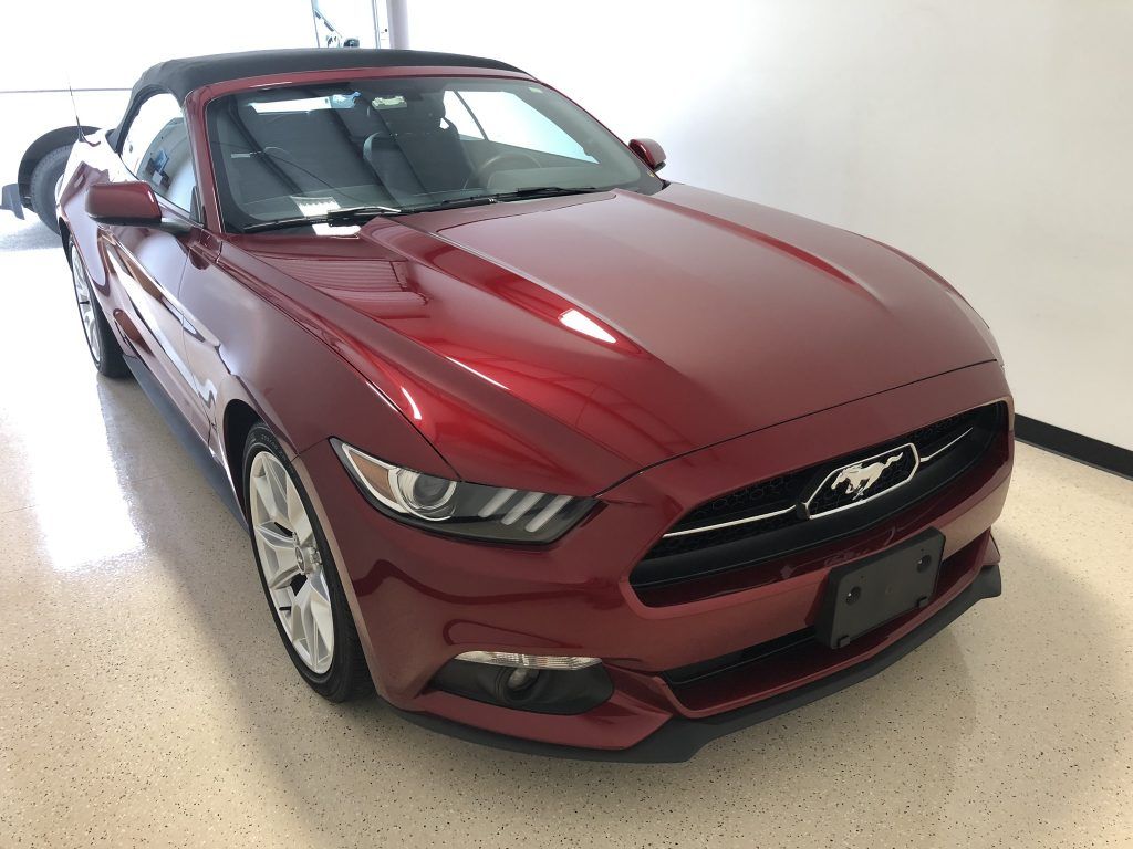 A red ford mustang convertible is parked in a garage.