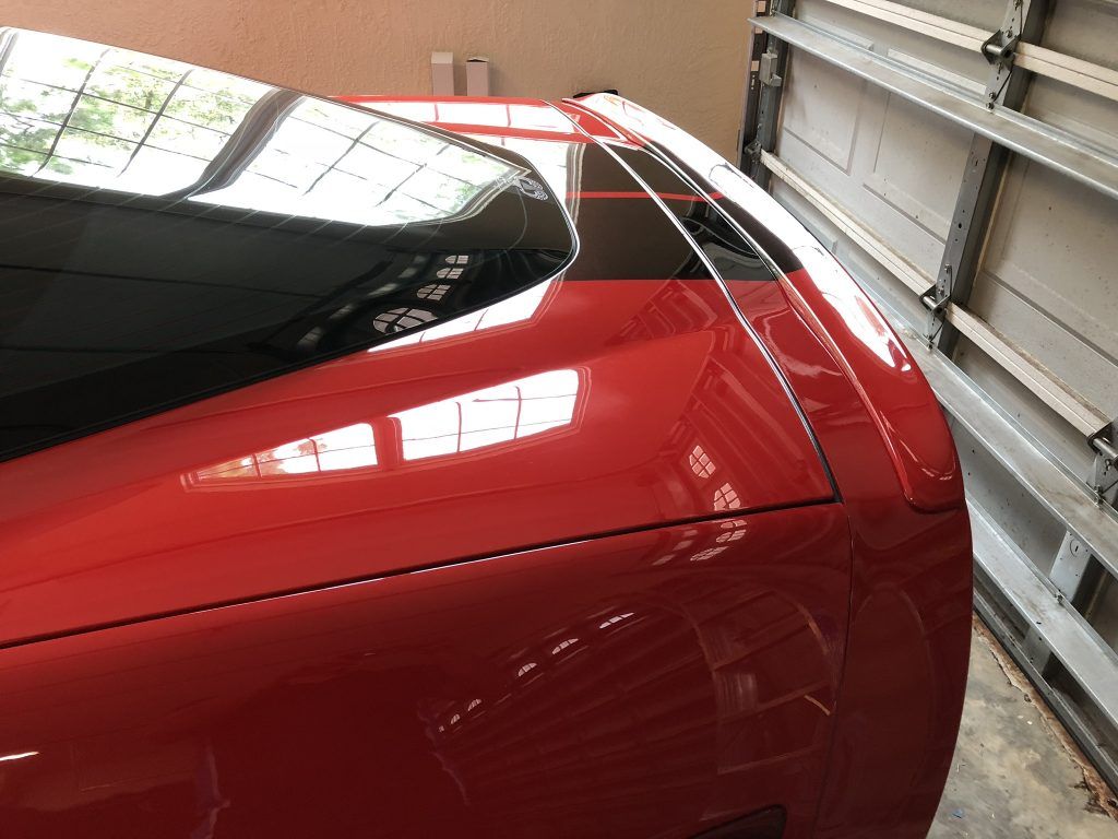 A red car is parked in a garage next to a garage door.