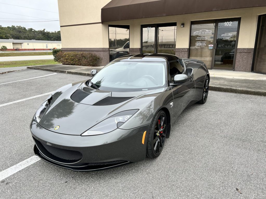 A gray sports car is parked in front of a building.