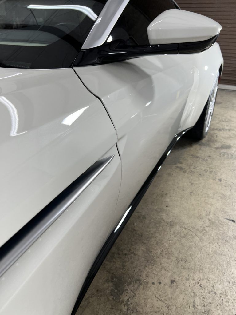 A white sports car is parked in a garage.