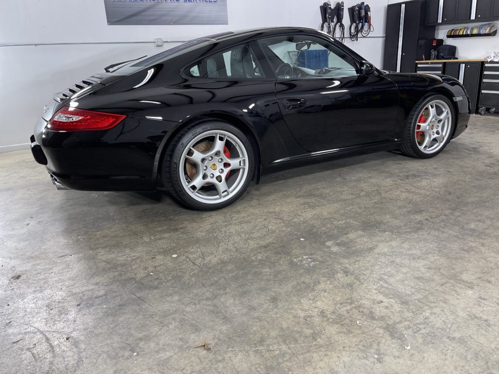 A black porsche 911 is parked in a garage.