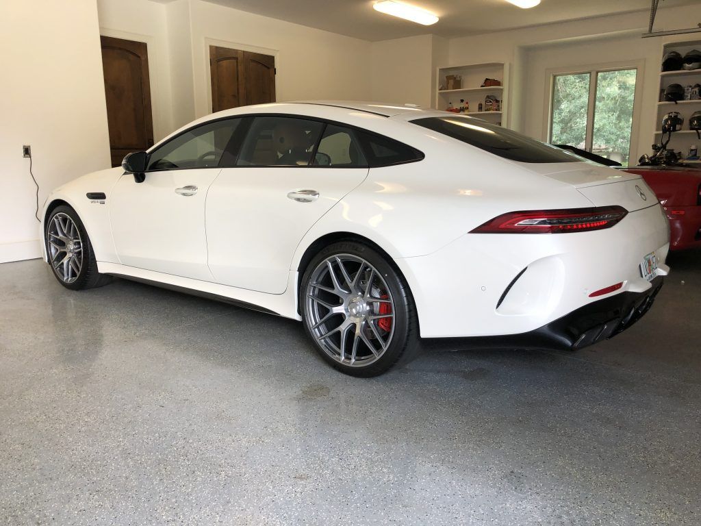 A white sports car is parked in a garage.