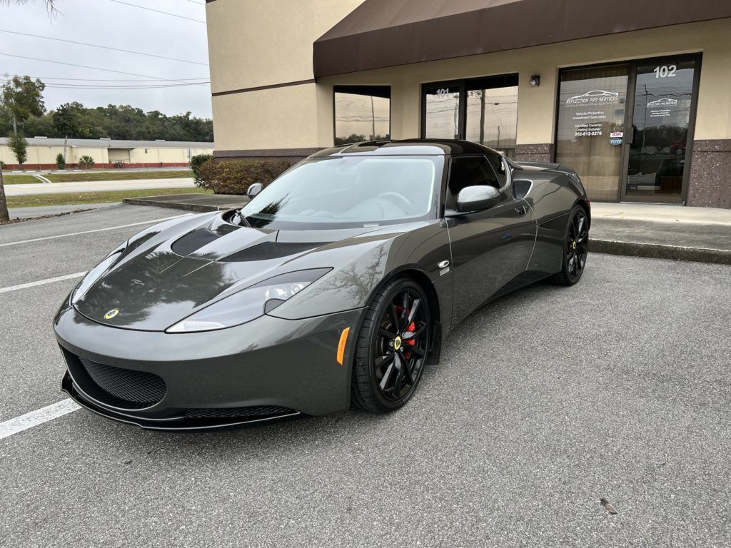 A gray sports car is parked in front of a building.