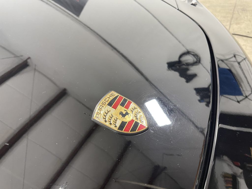 A porsche logo is on the hood of a black car