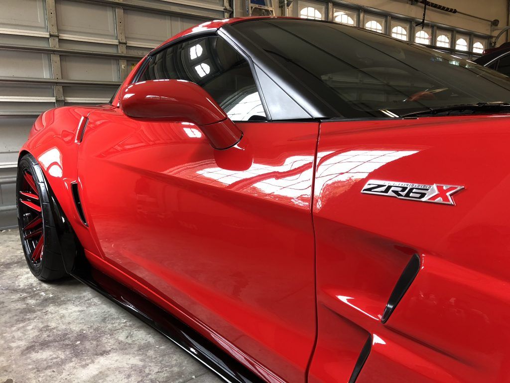 A red sports car is parked in front of a garage door.