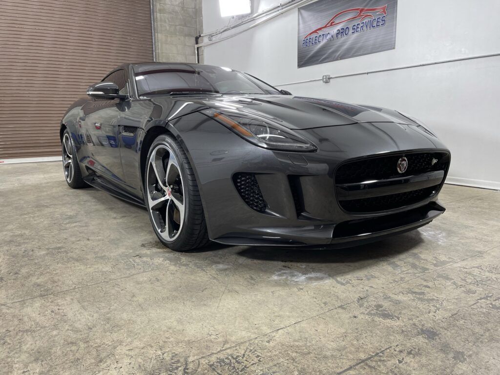 A black jaguar f type is parked in a garage.